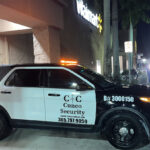 Cuneo Consulting security patrol car with flashing lights parked outside a Walmart at night.