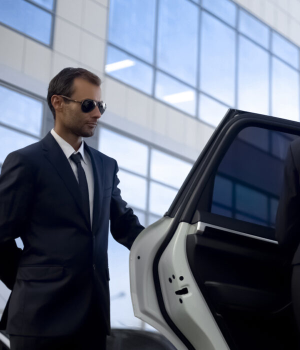 Professional security agent in a suit opening a car door, displaying vigilance and readiness