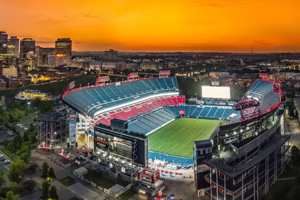 Aerial view of Nissan Stadium with the Nashville skyline at sunset.